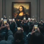 Immagine della Gioconda al Louvre, uno tra i musei più visitati e importanti al mondo, con davanti persone che fotografano con lo smartphone