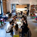 Interno tipico di ostelli con tavoli, libri, cucina e atmosfera condivisa