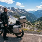 Motociclista impegnato in itinerario di mototurismo su una strada alpina