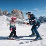 Una maestra di sci che fa imparare a sciare una bambina su una pista battuta con le dolomiti sullo sfondo