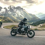 Due marche di moto europee impegnate sui tornanti di un passo alpino