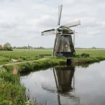 Immagine di un viaggio in Olanda che ritrae la tranquilla campagna primaverile con un mulino a vento tradizionale lungo un canale