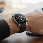 Uno smartwatch al polso di persona in un ambiente di lavoro con sullo sfondo scarpe da running ad indicare l'utilizzo vario di questi orologi digitali.
