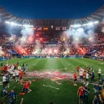 Uno stadio gremito di tifosi con giocatori in campo alla fine di una partita degli europei di calcio.