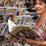 Signora che legge giornali di gossip in una edicola