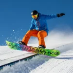 Immagine dinamica di uno snowboarder in azione su una pista innevata, con una tavola da snowboard colorata.