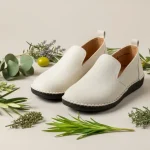 Fotografia editoriale di scarpe sostenibili in materiali naturali, esposte su fondo neutro con elementi vegetali