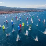 Immagine sulle regate veliche con una moltitudine di barche a vela in navigazione vicino alla costa su un percorso di gara
