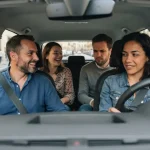 Quattro persone durante un viaggio in car pooling all'interno di un'auto guidata da una donna.
